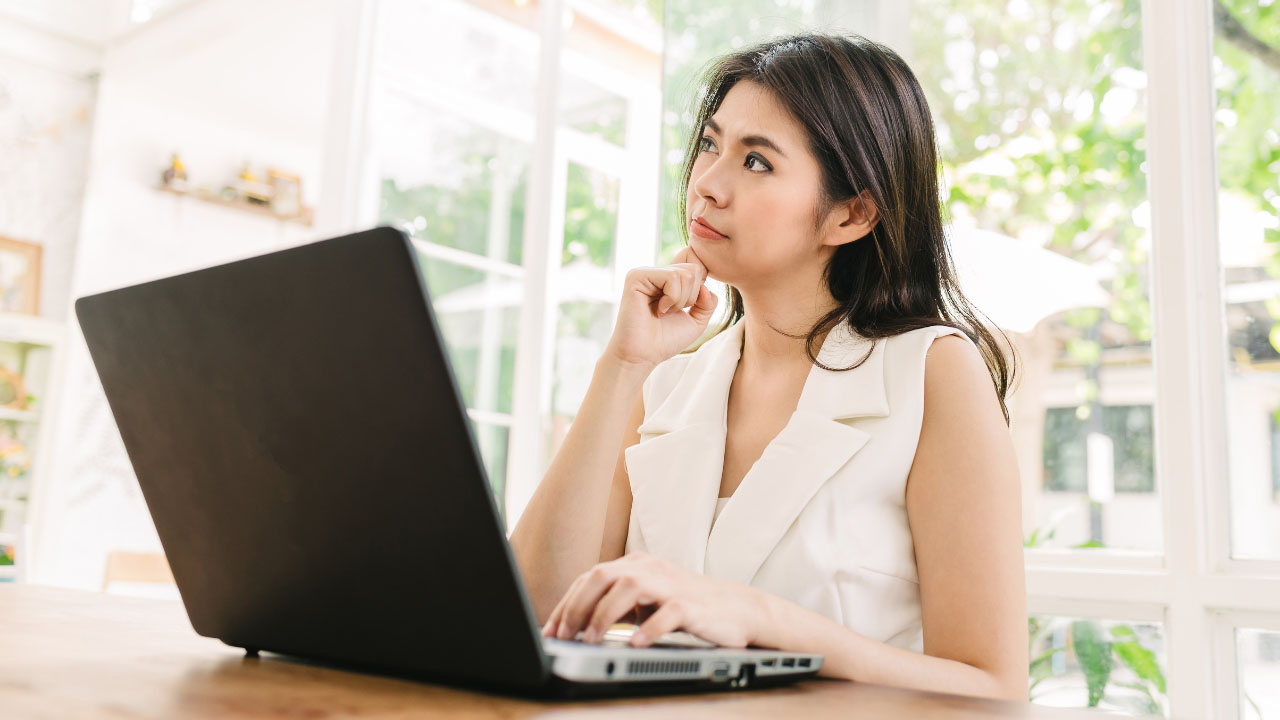 a woman considering her options while sitting in front of her laptop