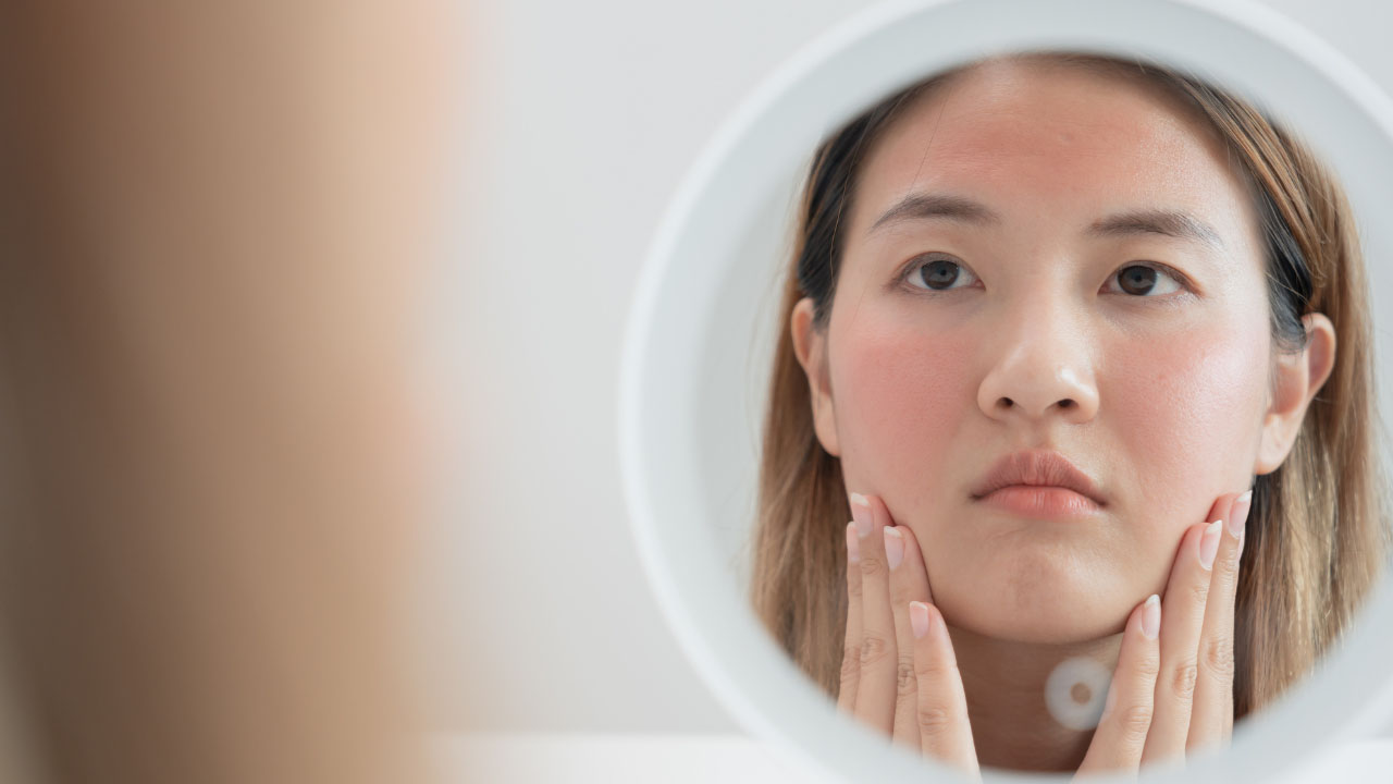 woman inspecting her face on the mirror